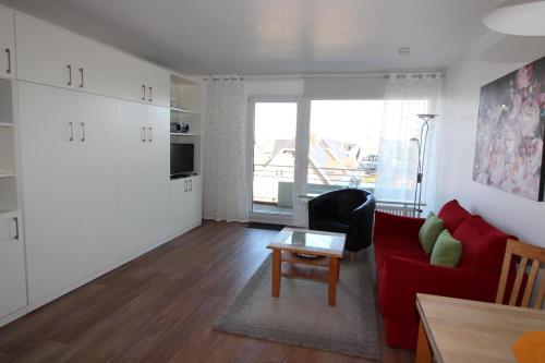 een woonkamer met een rode bank en een tafel bij Haus Norderhoog Wohnung 55 in Westerland