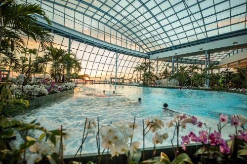 a pool in a building with people swimming in it at Suntago Village - Oficjalny nocleg Suntago in Mszczonów