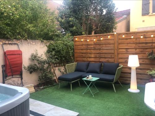 a patio with a couch and a table and a fence at Au Petit C'Alain in Toulouse