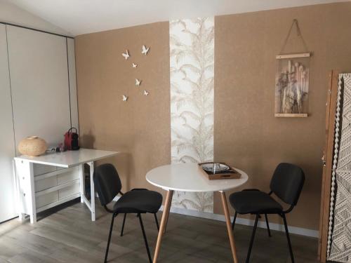 Au Petit C'Alain في تولوز: غرفة طعام مع طاولة وكراسي والطيور على الحائط