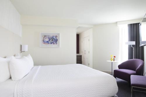 a bedroom with a white bed and a purple chair at Crowne Plaza Atlanta Perimeter at Ravinia by IHG in Atlanta