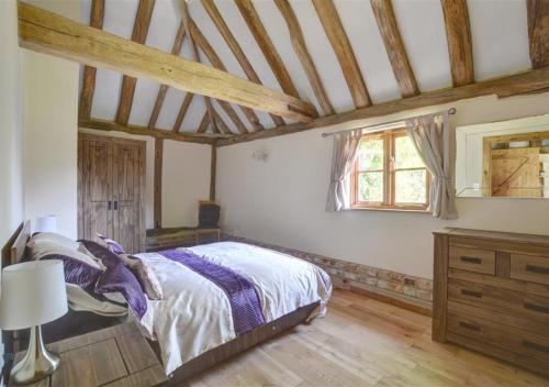 a bedroom with a bed and a wooden floor at Barley Byre in Rolvenden