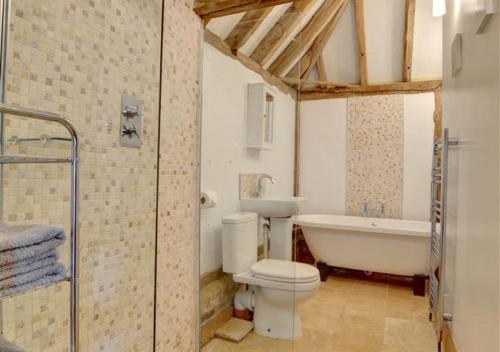 a bathroom with a tub and a toilet and a sink at Barley Byre in Rolvenden