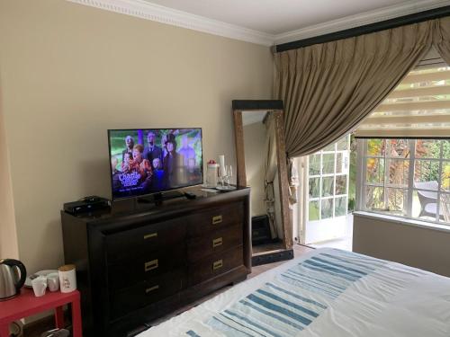 a bedroom with a bed and a television on a dresser at Safari Apartments -Beautiful 3 bedrooms, 10-seater dining , TV room, Garden & Pool in Johannesburg