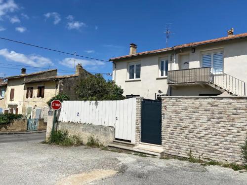 ein weißes Haus mit einem Zaun und einem Stoppschild in der Unterkunft Appartement avec climatisation proche du centre in Morières-lès-Avignon
