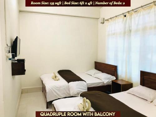 una habitación con 2 camas y un cartel que dice tamaño real de la habitación en Gracious Lodge, en Shillong