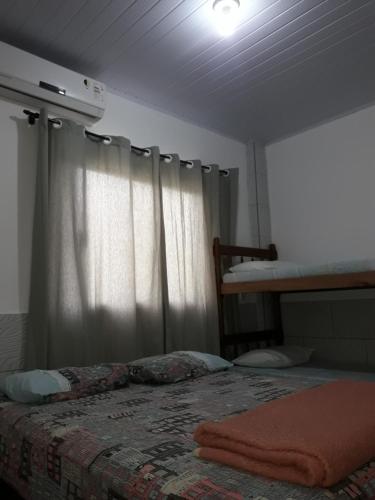 1 dormitorio con cama y ventana con cortina en Apartamentos C. Santos, en Penha