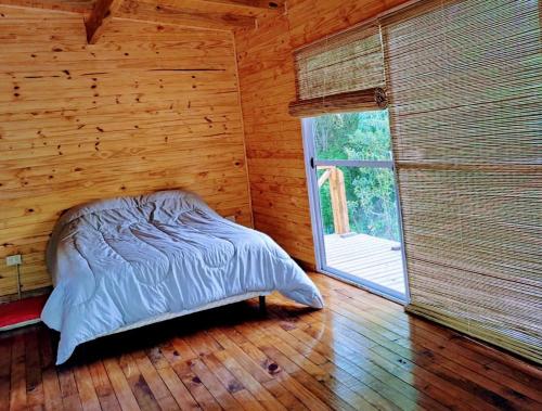 Cama en habitación de madera con ventana grande en Cabaña Delta.LaSofi en Tigre