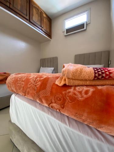 a bed with orange and white sheets and a window at Dar Bennis médina in Rabat