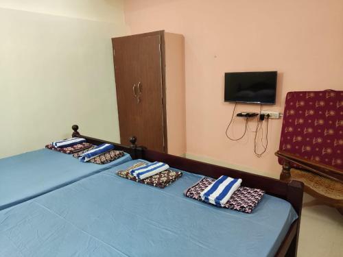 a bedroom with two beds with pillows and a tv at Sri Sai Farm House in Puducherry