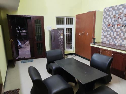 a room with a table and chairs and a kitchen at Sri Sai Farm House in Puducherry