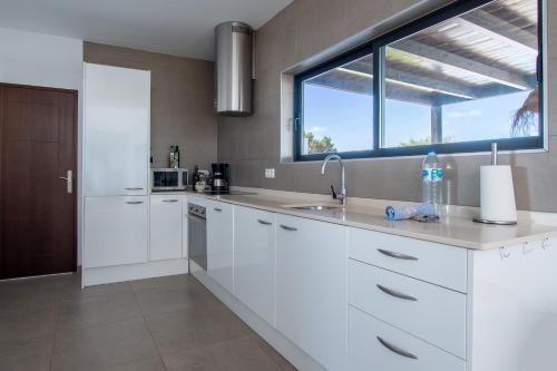 a white kitchen with a sink and a window at North Shore Villas, Villa MAKAI, Heated & Shared Pool in Lajares