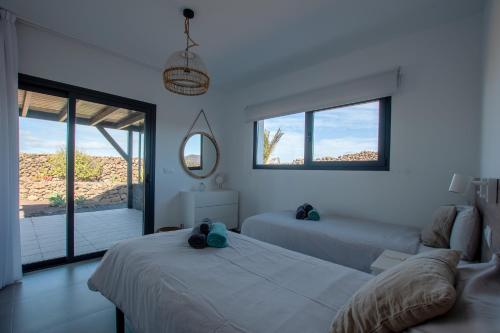 a white bedroom with two beds and a window at North Shore Villas, Villa MAKAI, Heated & Shared Pool in Lajares