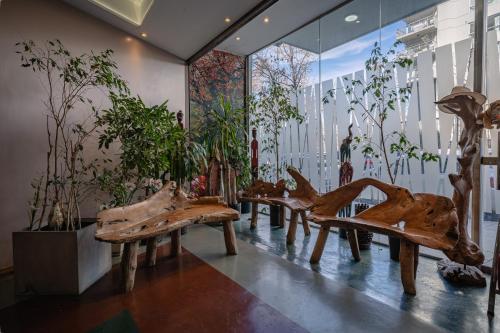 a group of wooden benches in a room with potted plants at Shoshana Hotel Boutique in Buenos Aires