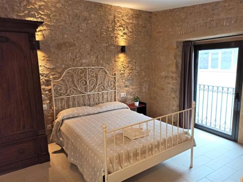 una camera con un letto bianco e un muro in pietra di Apartaments Fonda Comerç a Torroella de Montgrí
