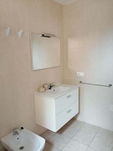 a white bathroom with a sink and a mirror at Casa Nube in Sant Francesc Xavier