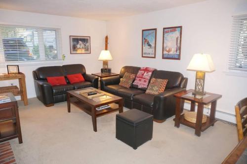 a living room with black leather couches and tables at Dean St Condos in Aspen