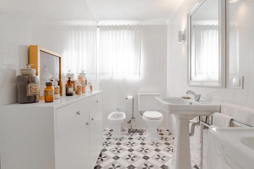 a white bathroom with a toilet and a sink at Casa da Avó Bia in Estremoz