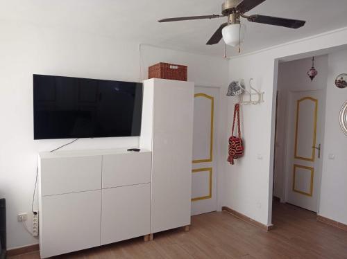 un centro de entretenimiento blanco con TV de pantalla plana. en Clean and comfortable budget flat, en Fuengirola