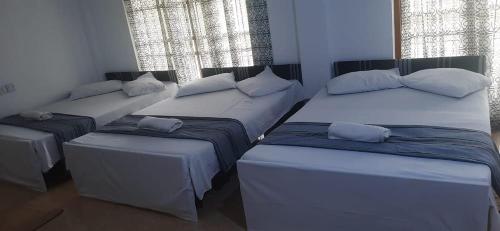 um quarto com três camas e duas janelas em Fair View Bungalow em Kataragama