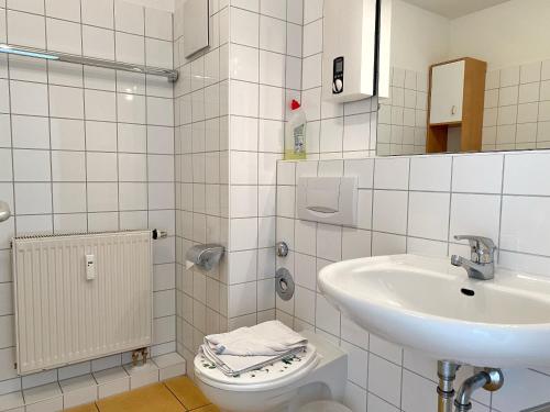 een witte badkamer met een wastafel en een toilet bij Appartementhaus Victoria - Fewo Meeresrauschen in Sassnitz