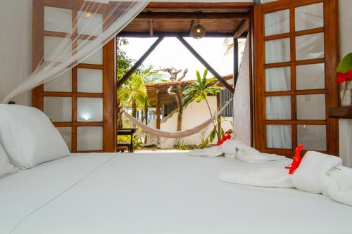 um quarto com uma cama branca e uma janela em Travel Inn Trancoso Suítes em Trancoso