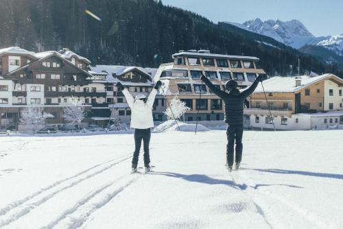 dos personas de pie en la nieve con los brazos en alto en DAS GERLOS - Boutique Hotel en Gerlos