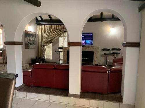 a living room with two red couches and a fireplace at Safari Apartments -Beautiful 3 bedrooms, 10-seater dining , TV room, Garden & Pool in Johannesburg