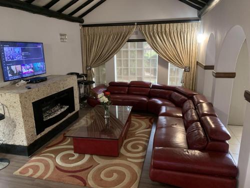 a living room with a leather couch and a fireplace at Safari Apartments -Beautiful 3 bedrooms, 10-seater dining , TV room, Garden & Pool in Johannesburg