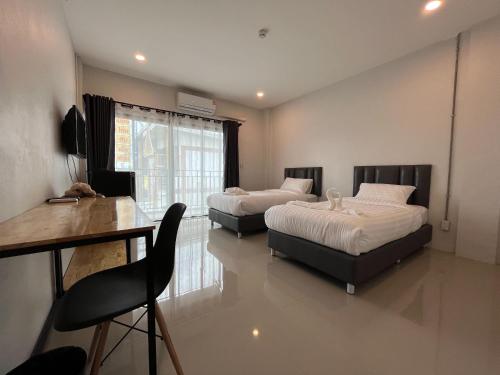 a bedroom with two beds and a table and a desk at Life Hotel Rong Khun in Ban Mai