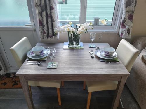 a wooden table with chairs and a vase of flowers at Nicks and Carmels by the Lake in Carnforth