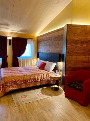 a bedroom with a bed and a red chair at Hotel Chaberton in Cesana Torinese