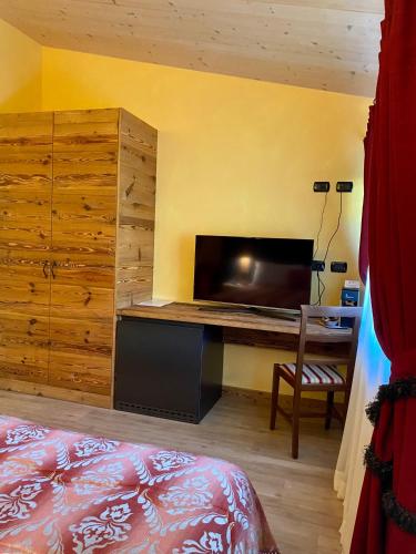 a bedroom with a bed and a desk with a television at Hotel Chaberton in Cesana Torinese