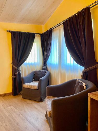 a living room with two chairs and curtains at Hotel Chaberton in Cesana Torinese