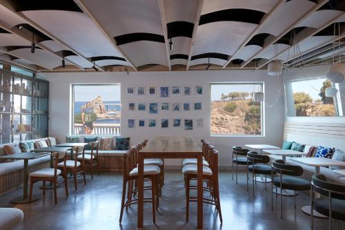 uma sala de jantar com mesas, cadeiras e janelas em Hôtel de La Plage em Biarritz