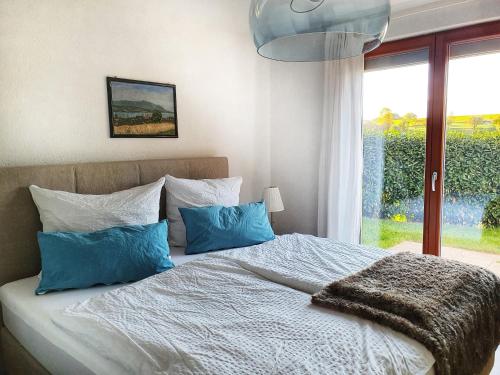 Waldenbuch的住宿－Komfort Appartement Panoramaweg，一间卧室配有一张带蓝色枕头的床和一扇窗户。