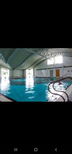 a large swimming pool with blue water in a building at Nicks and Carmels by the Lake in Carnforth
