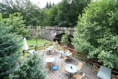 a wooden deck with tables and chairs and a bridge at Chalet du Montal in Dun-les-Places