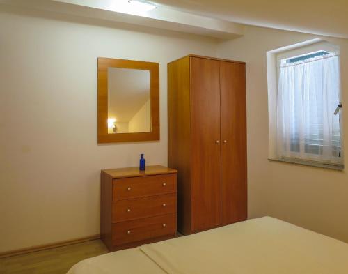 a bedroom with a wooden cabinet and a dresser at Apartments Janči, Murter (Croatia) in Murter