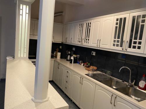 a kitchen with white cabinets and a sink at Ballo Apartments in Gjirokastër