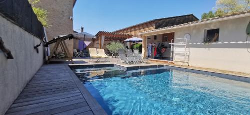 a swimming pool with a wooden walkway next to a house at L'AUTHENTIQUE in Eurre