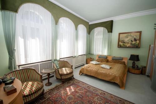 Schlafzimmer mit einem Bett, Stühlen und Fenstern in der Unterkunft Luxus Villa EMG Dortmund nah Düsseldorf, Köln, Essen in Ennepetal