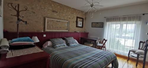 a bedroom with a bed and a table and a window at L'AUTHENTIQUE in Eurre