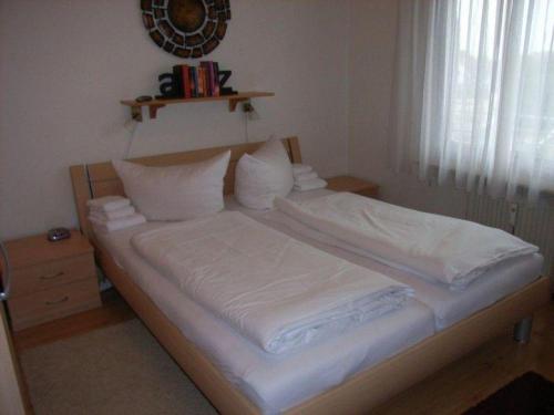 ein Bett mit weißer Bettwäsche und Kissen in einem Schlafzimmer in der Unterkunft Haus Norderhoog Wohnung 56 in Westerland