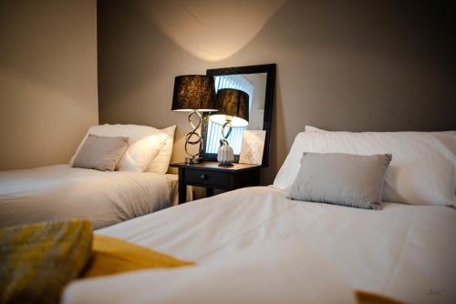 a bedroom with two beds and a lamp and a mirror at Liverpool At Gloucester Road - Infinity Apartments in Liverpool