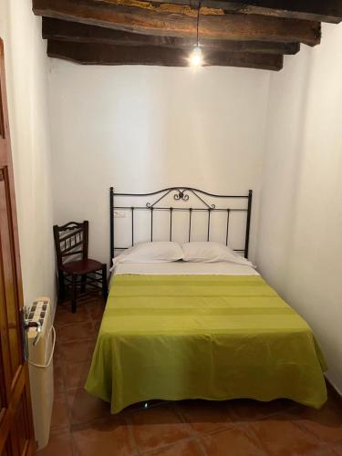 1 dormitorio con 1 cama con manta verde en CASA M'GUIRE, en Pampaneira