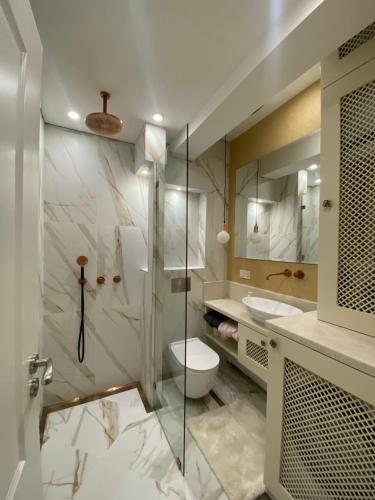 a bathroom with a toilet and a glass shower at Classic and New brand Apartment San Stefano 9 in Varna City