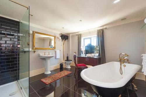 a bathroom with a tub and a sink and a toilet at Hall Farmhouse.. dog friendly, large outdoor pool, BBQ and fire pit in King's Lynn