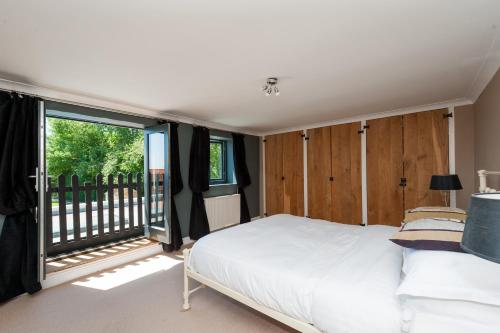 a bedroom with a bed and a large window at Hall Farmhouse.. dog friendly, large outdoor pool, BBQ and fire pit in King's Lynn