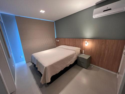 a small bedroom with a bed and a blue wall at Cobertura Velejar em Condomínio Clube - com Área de Lazer in Governador Celso Ramos